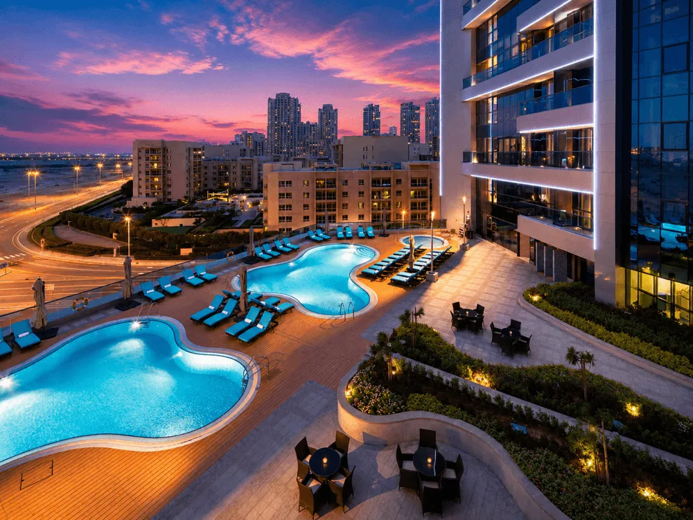 Rooftop swimming pools with Al Barsha high-rise buildings at sunset