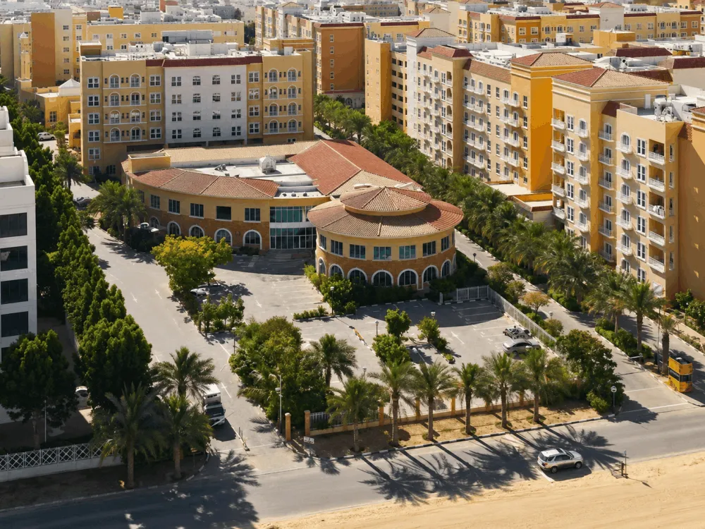 Aerial view of apartment buildings and palm-lined streets in Dubai Investment Park
