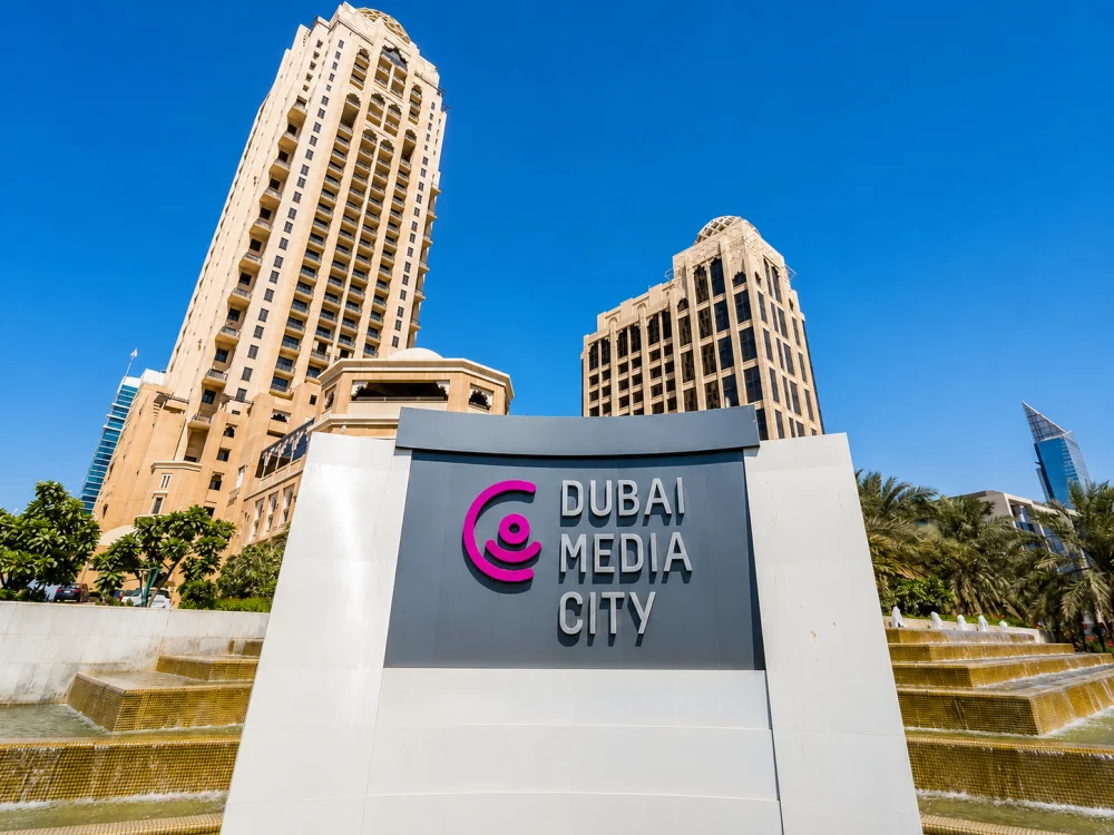 Dubai Media City sign with high-rise office towers and fountains.