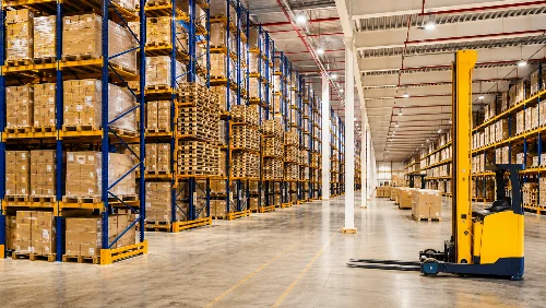 Organised warehouse with pallet racks, stored cartons and yellow forklift in a wide loading aisle